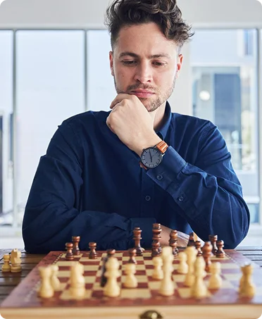 Een jonge man die zich richt op het schaakbord terwijl hij zijn volgende tactische zet overweegt.